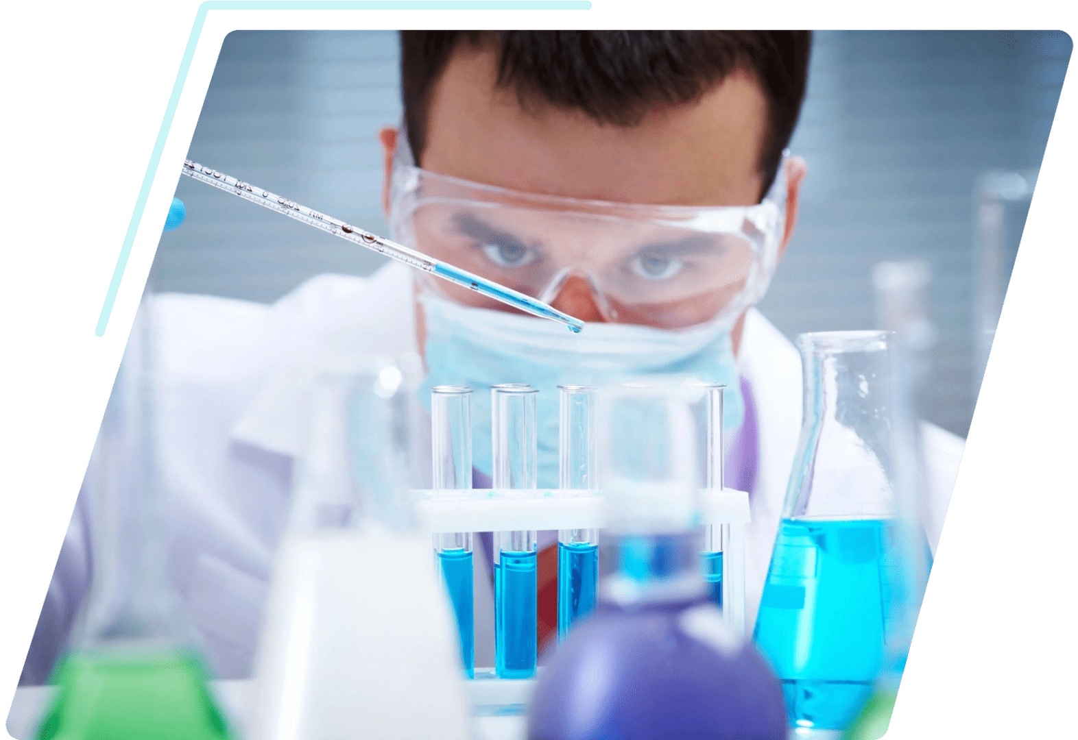 A man in lab coat and goggles looking at some liquid.
